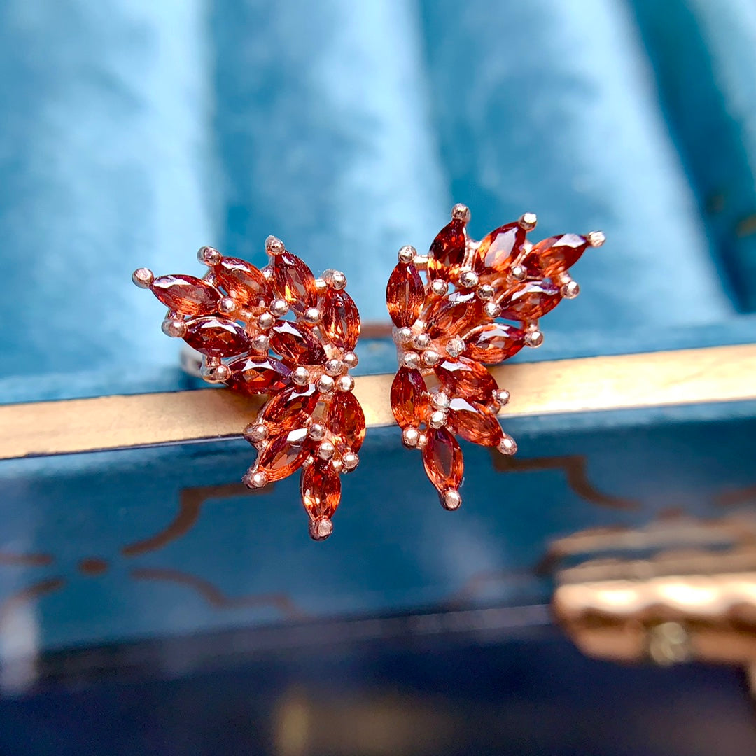 A ring made with multiple gemstones in a butterfly design, each handcrafted with 22 stones. Available in various colors, featuring natural garnet, topaz, tanzanite, and diopside.